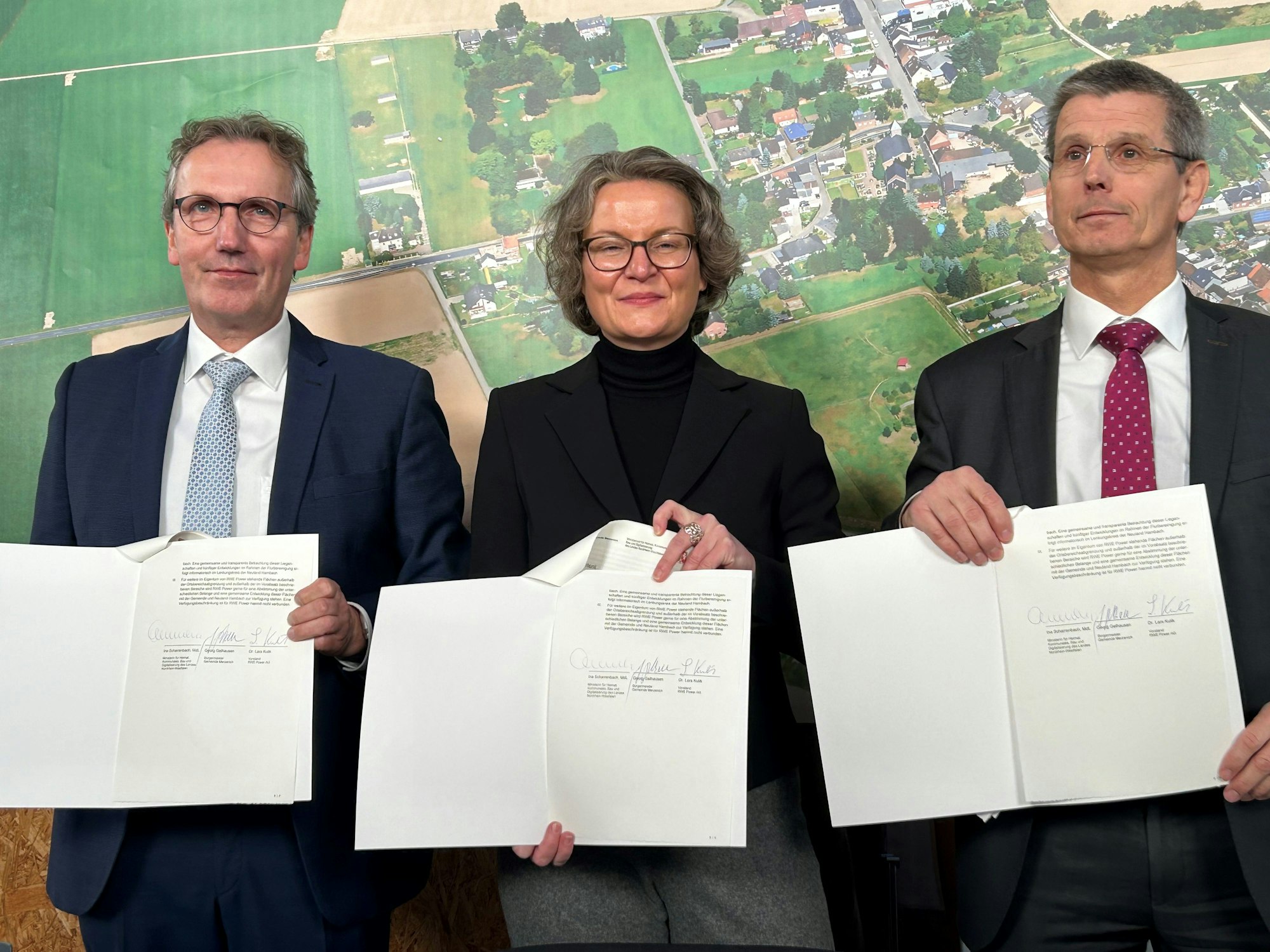 Die drei Beteiligten sind im Gruppenbild zu sehen und halten je ein Exemplar des Übergabevertrags vor sich: Merzenichs Bürgermeister Georg Gelhausen, Kommunalministerin Ina Scharrenbach und RWE-Vorstand Lars Kulik.