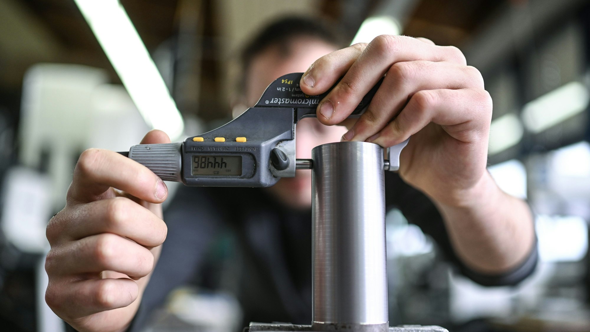 Ein Auszubildender im Metall-Handwerk misst in einem Ausbildungszentrum die Dicke eines Werkstücks.