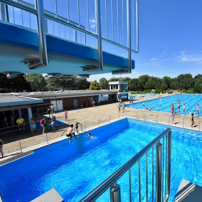 Blick auf den hohen Sprungturm und die blauen Becken des Freibades in Sankt Augustin.