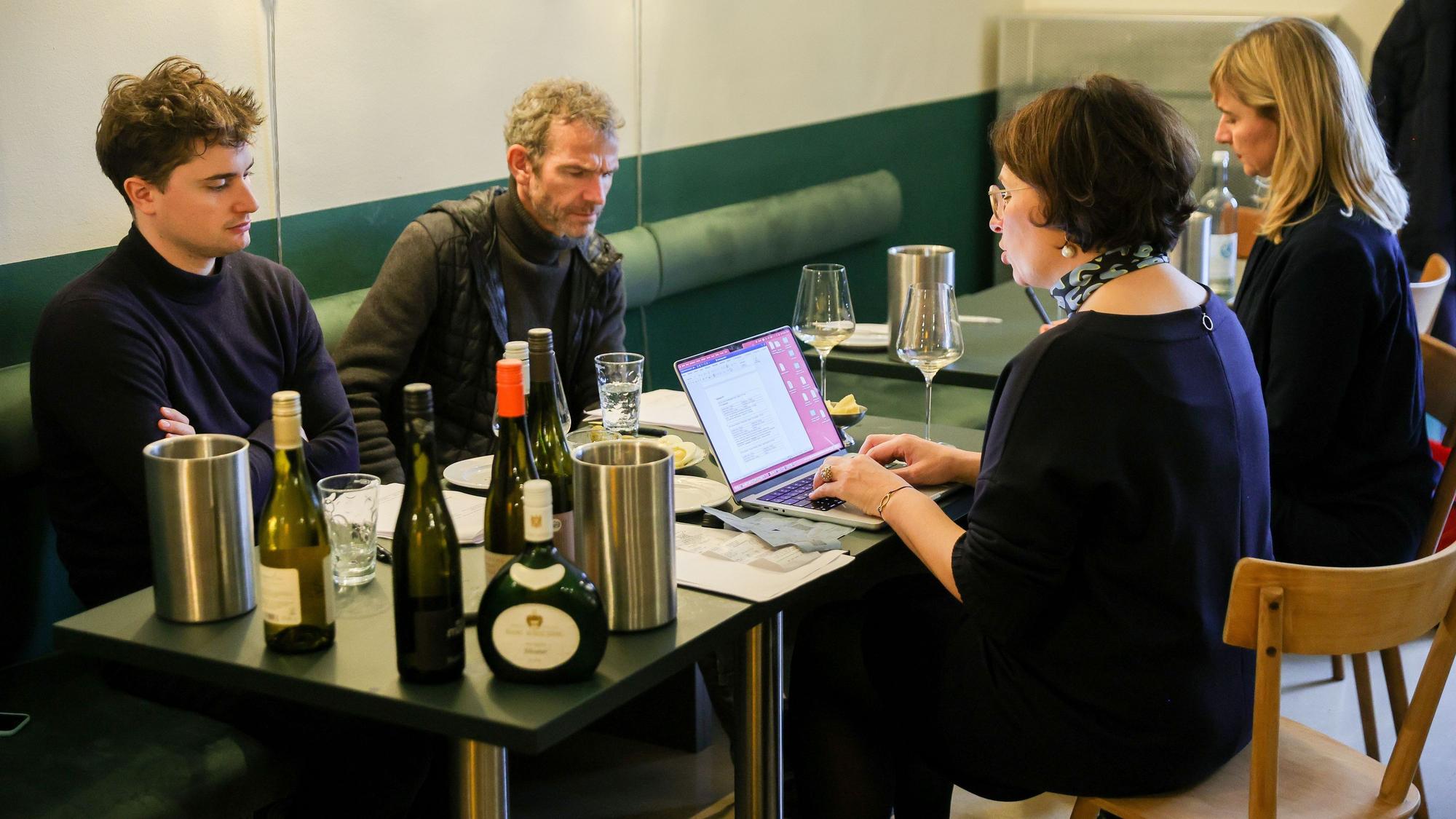 Vier Menschen sitzen an einem Tisch und probieren Wein.
