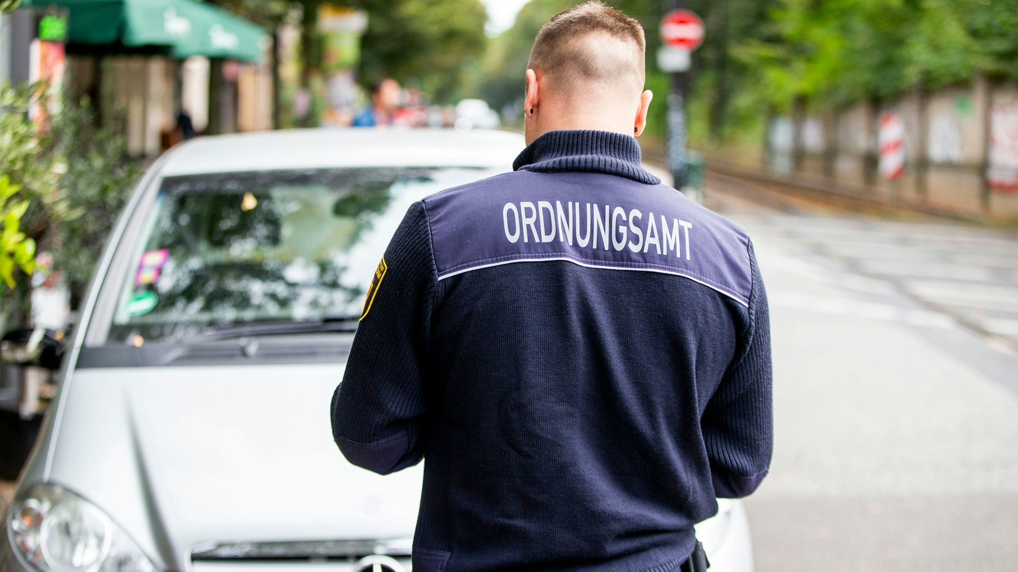Angestellter des Ordnungsamtes notiert Falschparker.