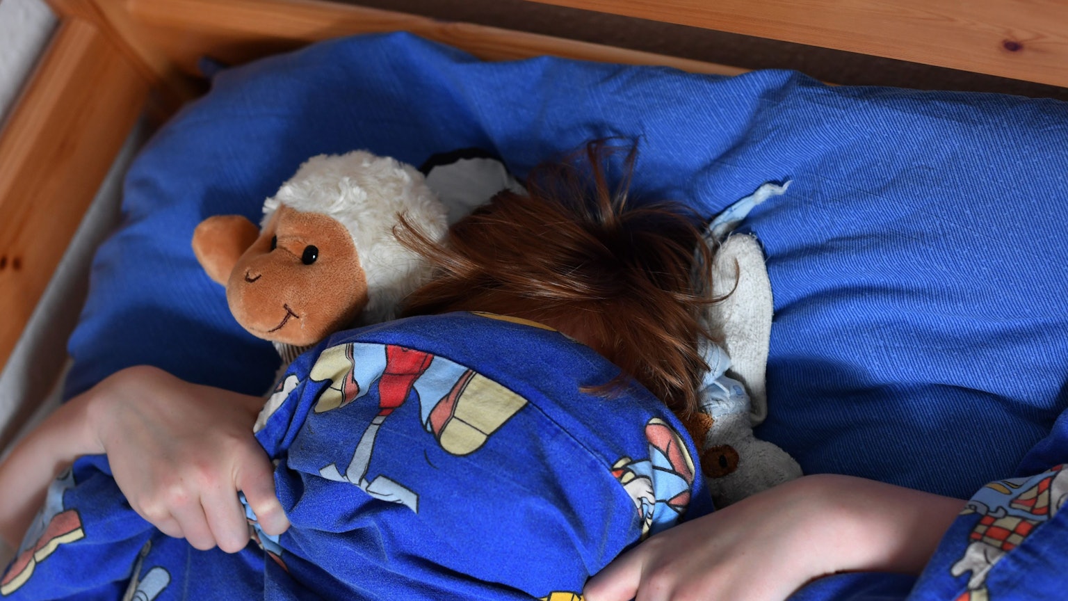 Ein zehnjähriger Junge hat sich seine Bettdecke über das Gesicht gezogen.