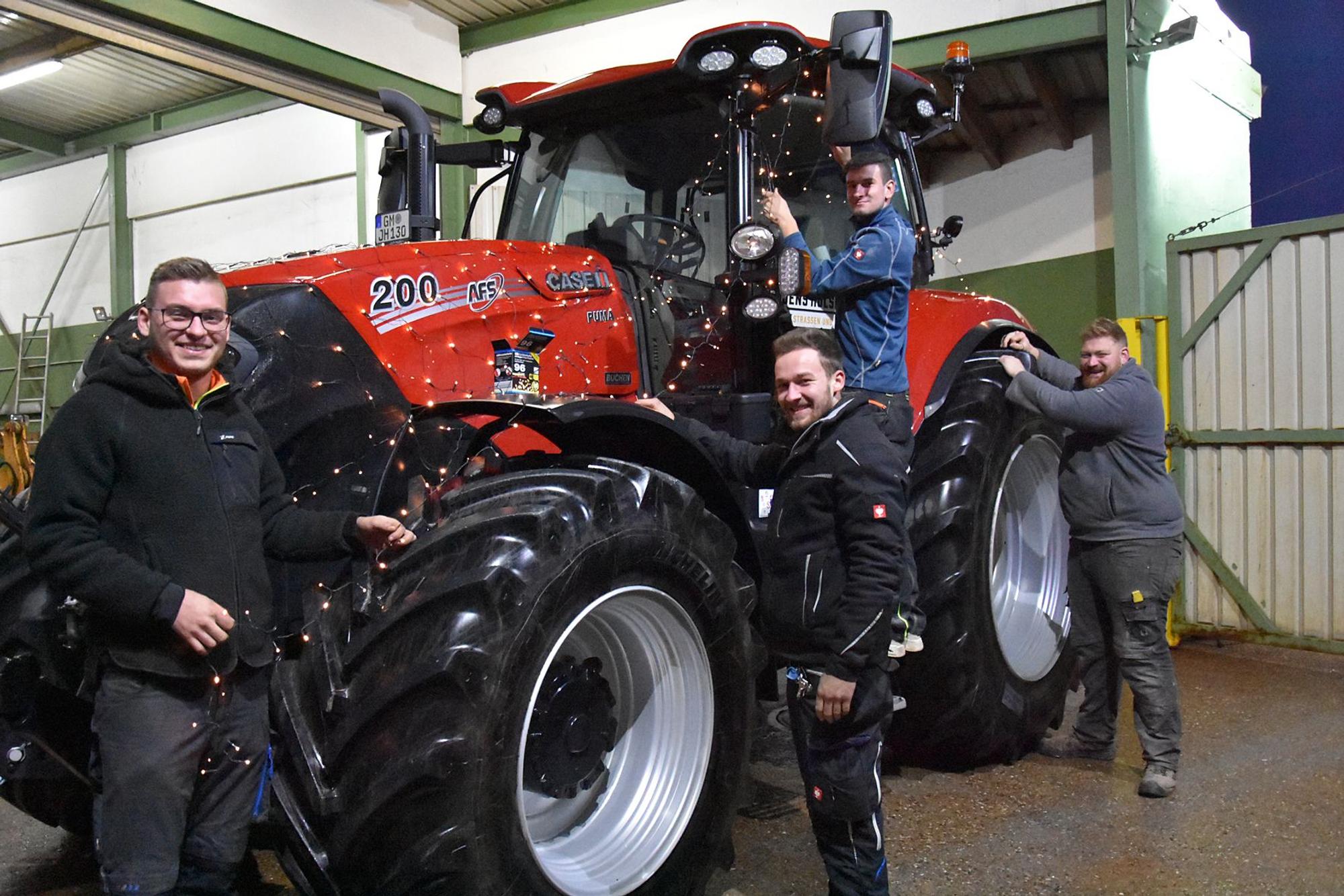Tom Kollenbach, André Becker, Chris Voigt, Maik Harrock schmücken einen roten Traktor mit Lichterketten für die Lichterfahrt 2023.