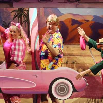 Anna Rixmann, Tom Simon und Martina Klinke als Hänneschen-Figuren in Barbie-Version mit einem pinkfarbenen Papp-Auto.