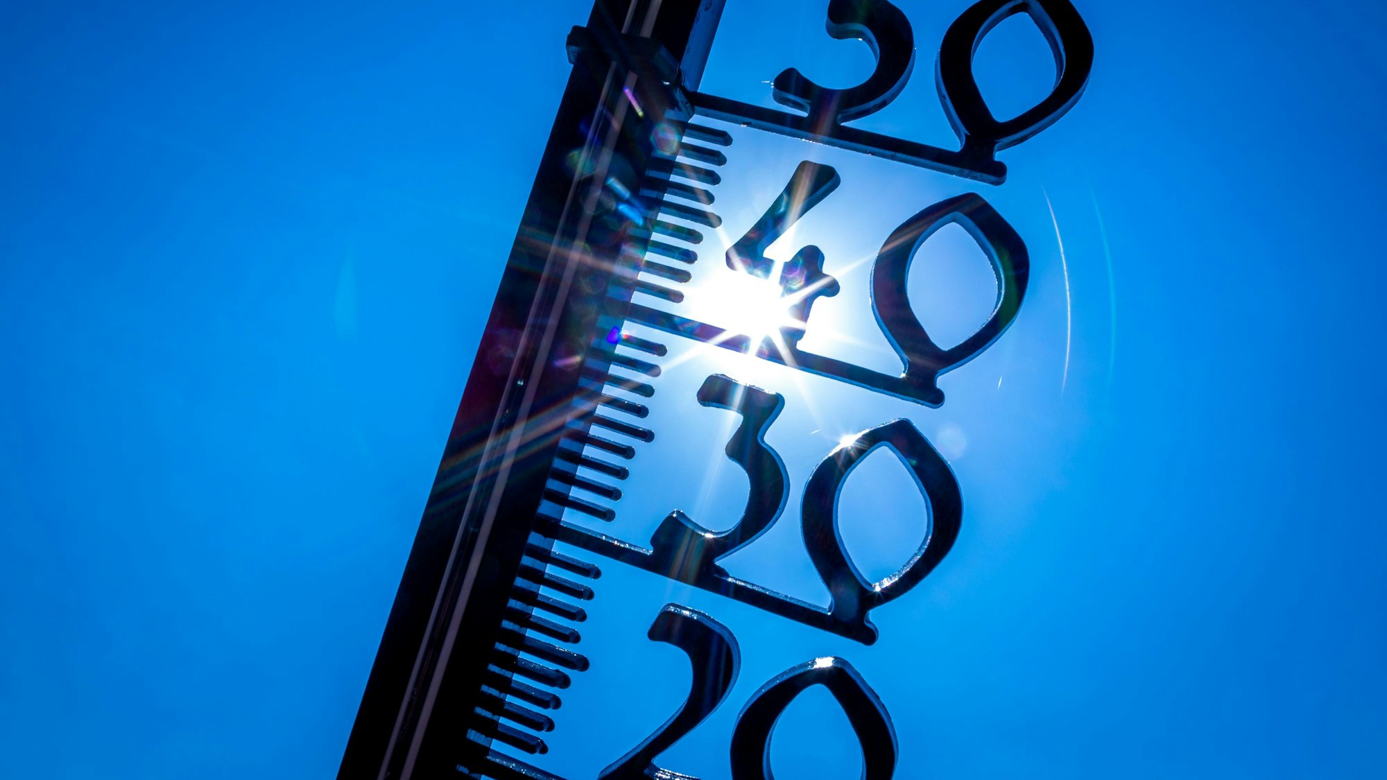 Ein Thermometer vor einem blauen Himmel und gleißender Sonne.