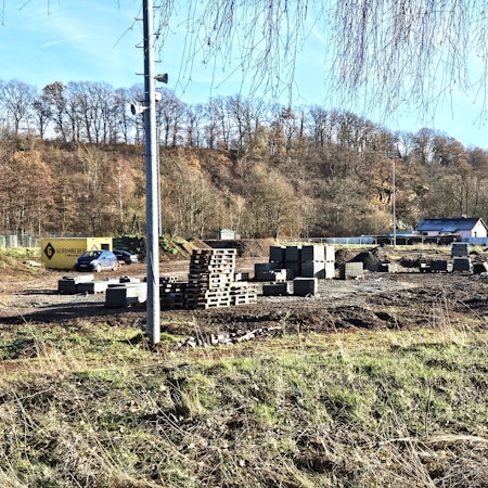 Blick auf den ehemaligen Sportplatz in Kall, auf dem Paletten, Pflastersteine und Erdhügel zu sehen sind.