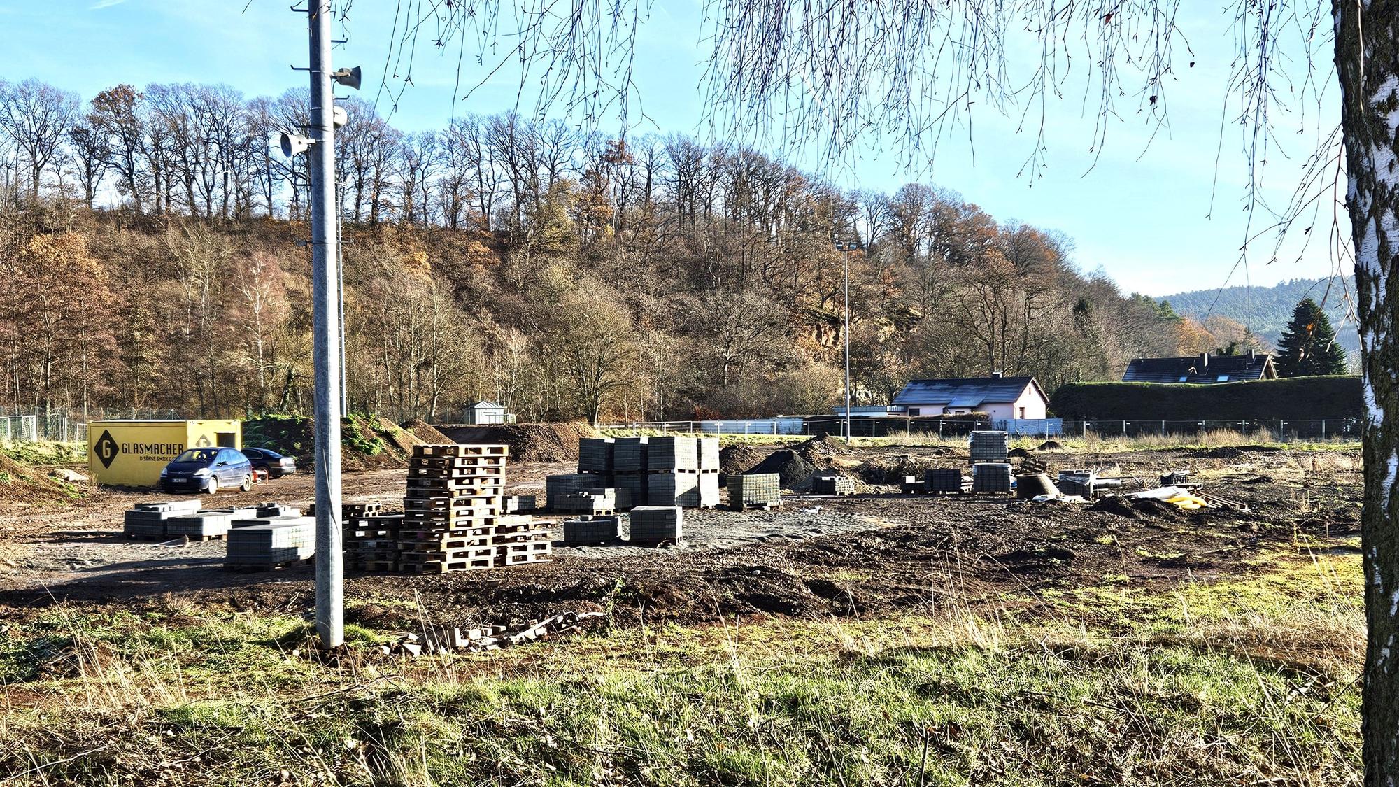 Blick auf den ehemaligen Sportplatz in Kall, auf dem Paletten, Pflastersteine und Erdhügel zu sehen sind.