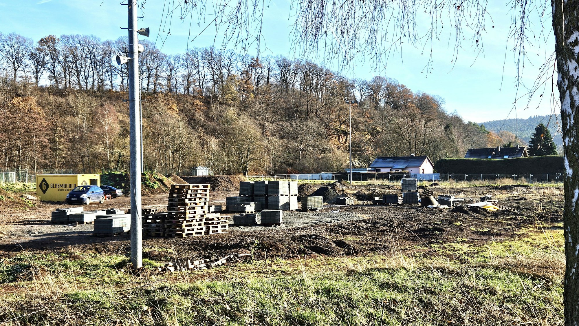 Blick auf den ehemaligen Sportplatz in Kall, auf dem Paletten, Pflastersteine und Erdhügel zu sehen sind.