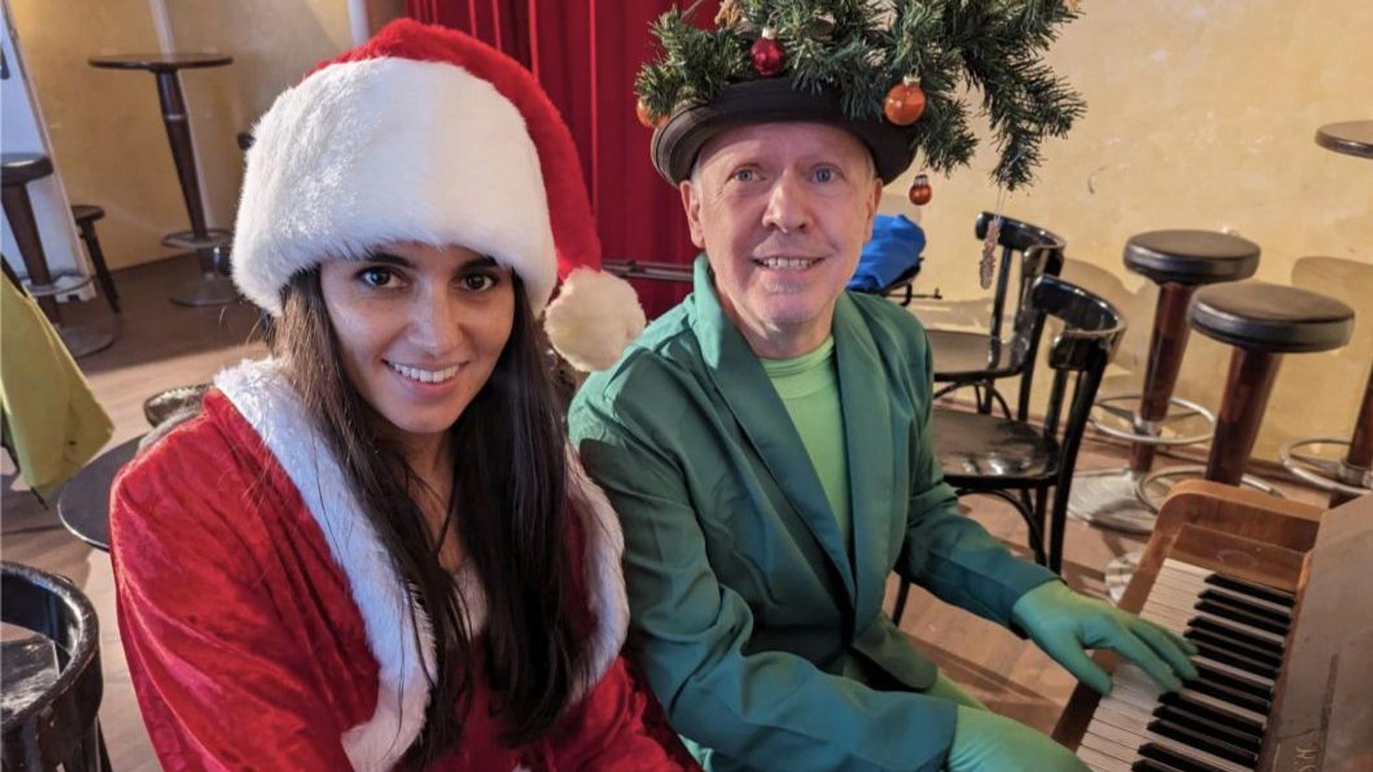 Samira Zand und Dietmar Kolvenbach sitzen in weihnachtlichen Kostümen am Klavier.