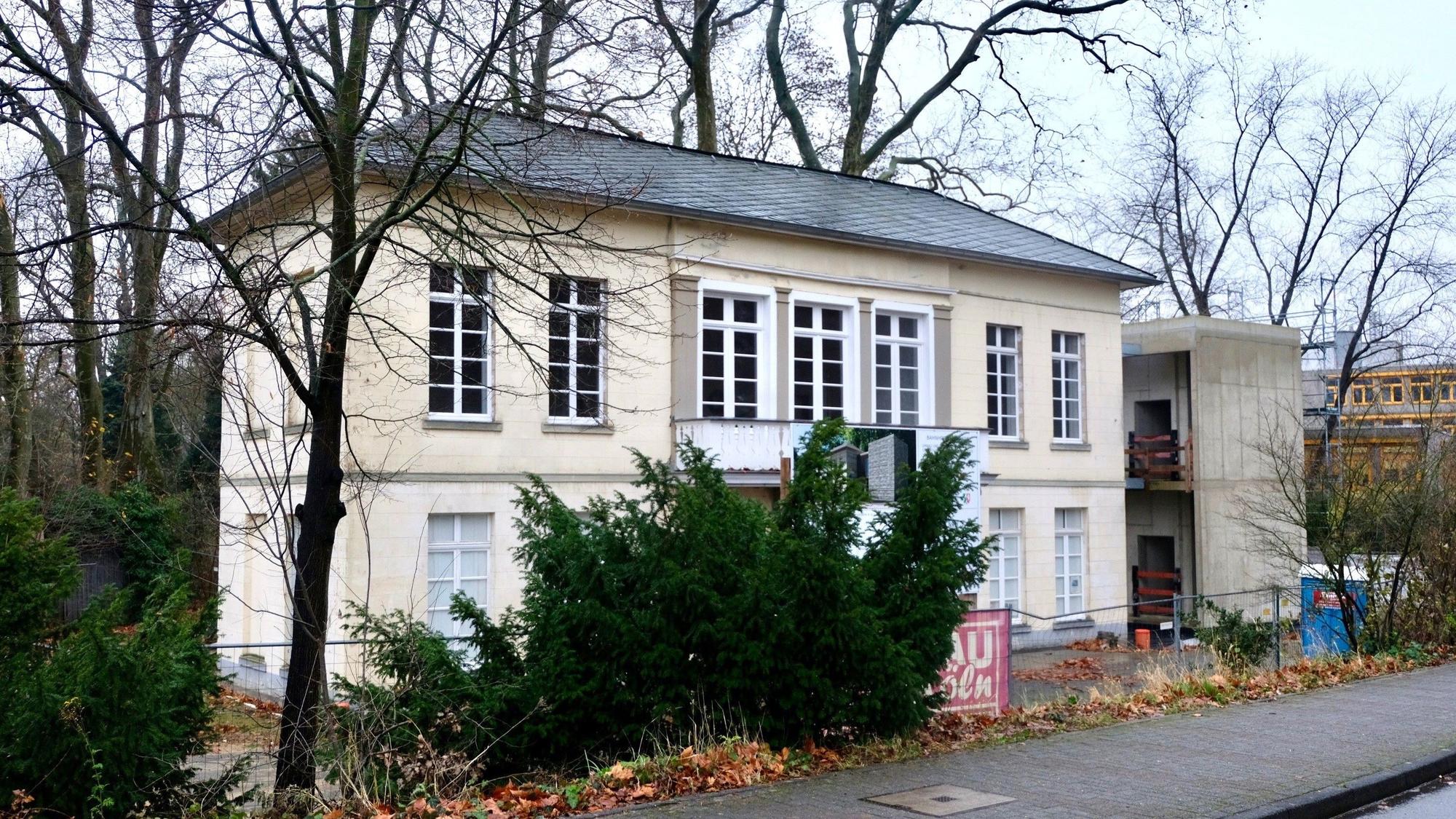 Blick auf ein Gebäude, das von Bäumen und Bauzäunen umgeben ist.