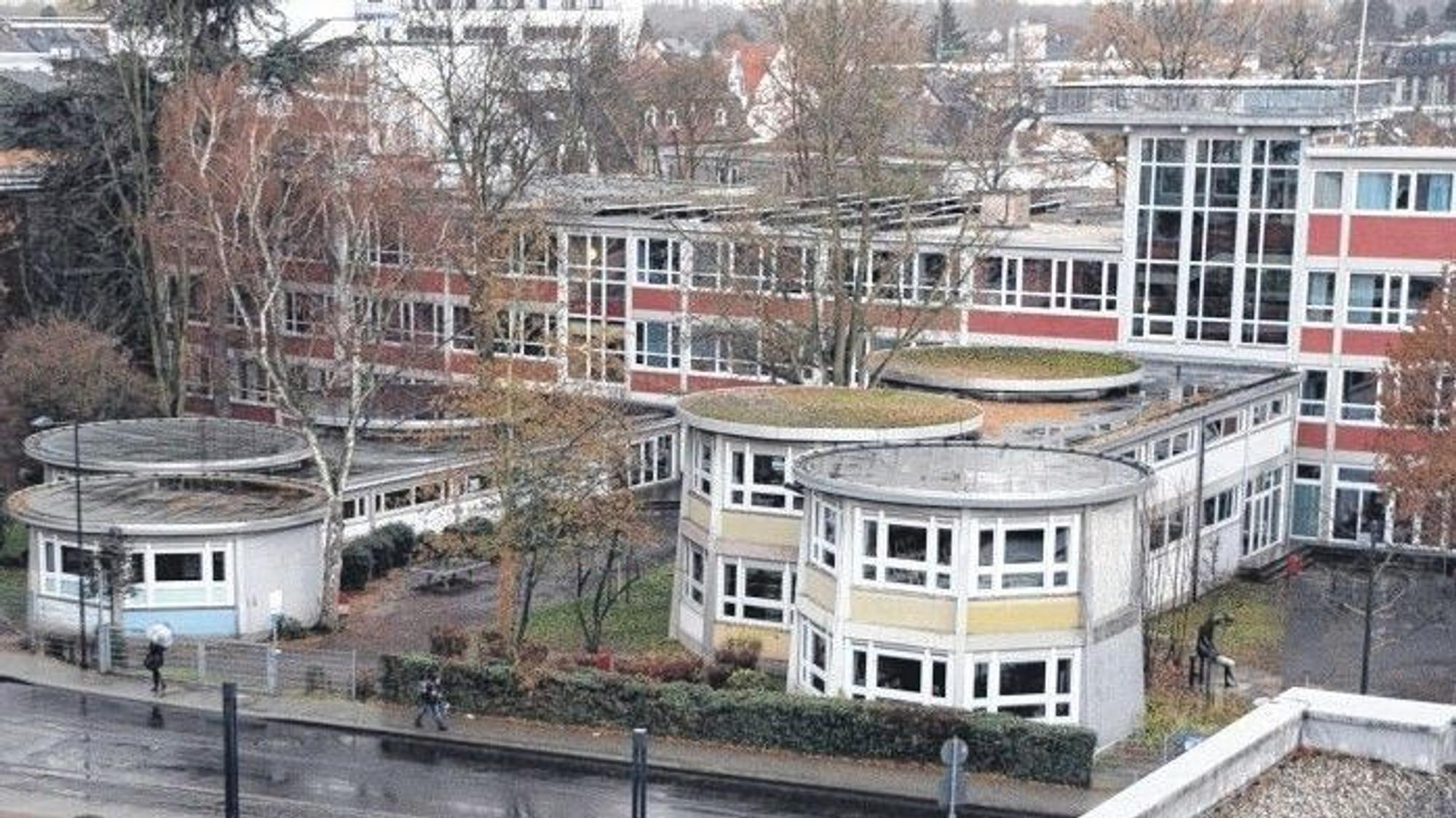 Eine Schule mit pavillonförmigen Trakten und Fassadenelementen in Pastelltönen Gelb, Rot und Hellblau