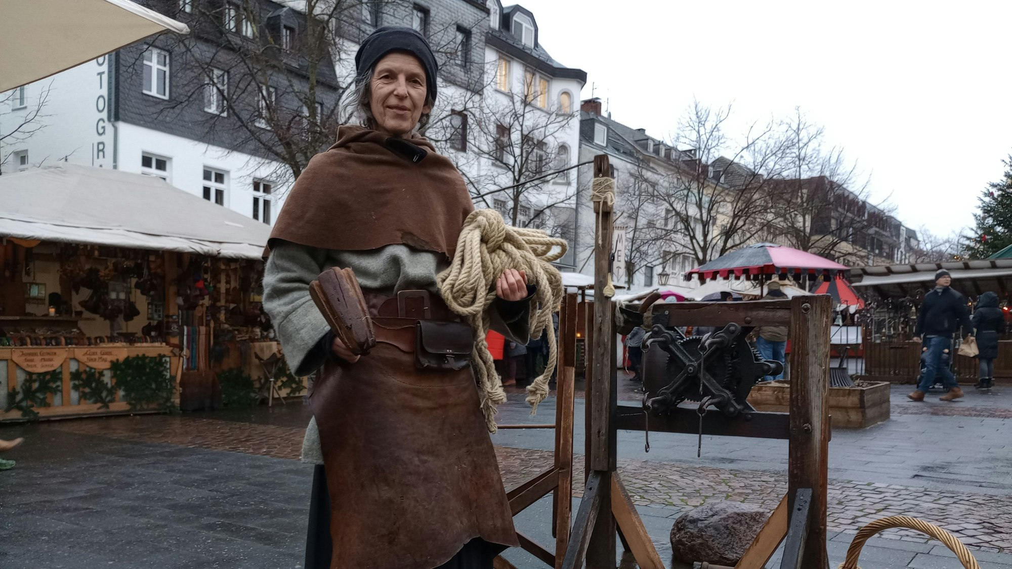 Eine Frau in mittelalterlicher Tracht hat ein Seil in der Hand.