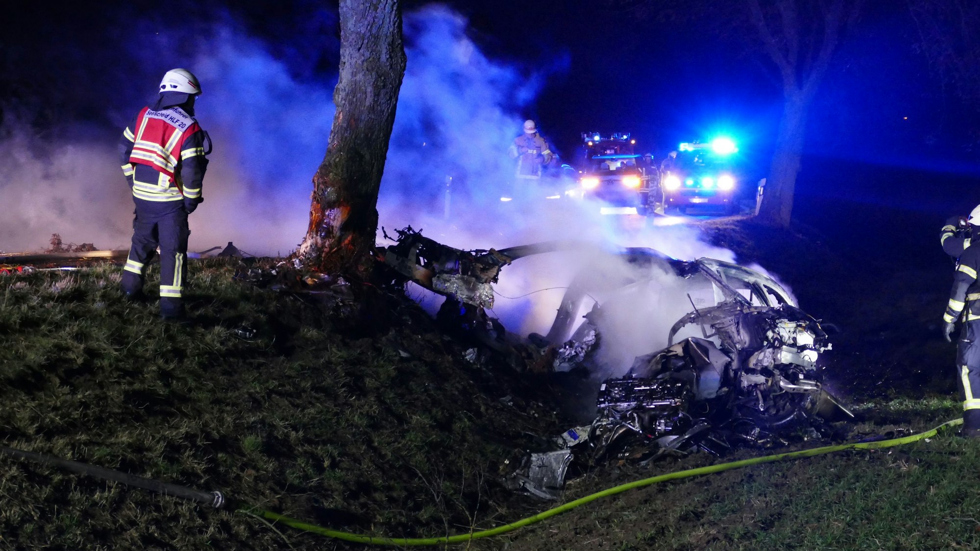 Feuerwehrleute an einem qualmenden Fahrzeug.