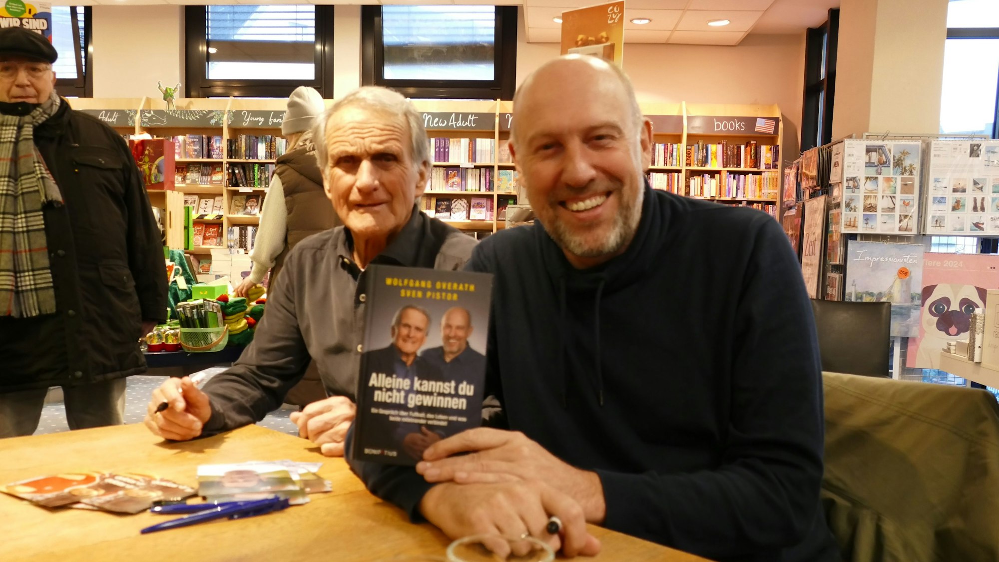Zwei Männer an einem Tisch präsentieren ein Buch