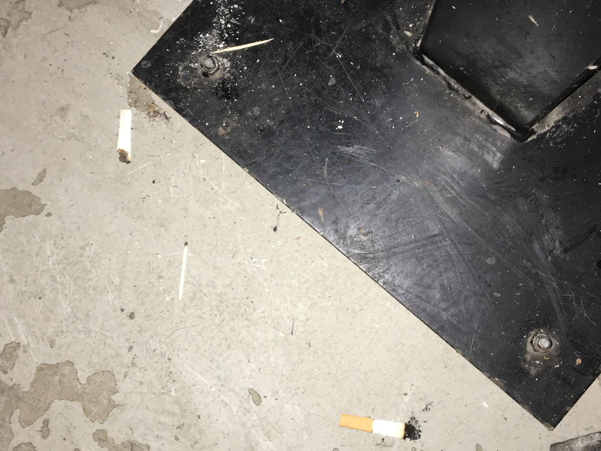Die Aufnahme zeigt den dreckigen Barboden und ausgedrückte Zigarettenstummel nach einer Partynacht.