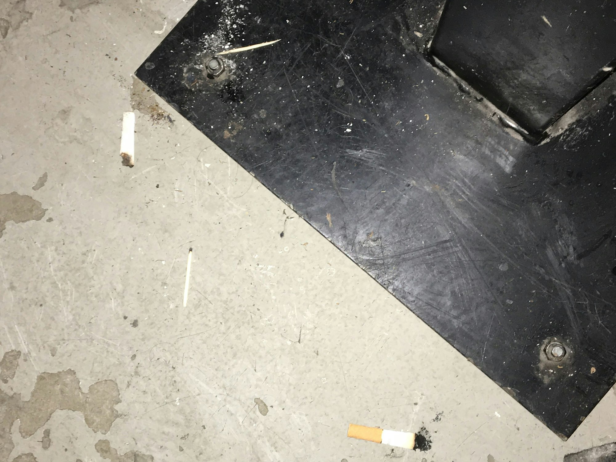 Die Aufnahme zeigt den dreckigen Barboden und ausgedrückte Zigarettenstummel nach einer Partynacht.