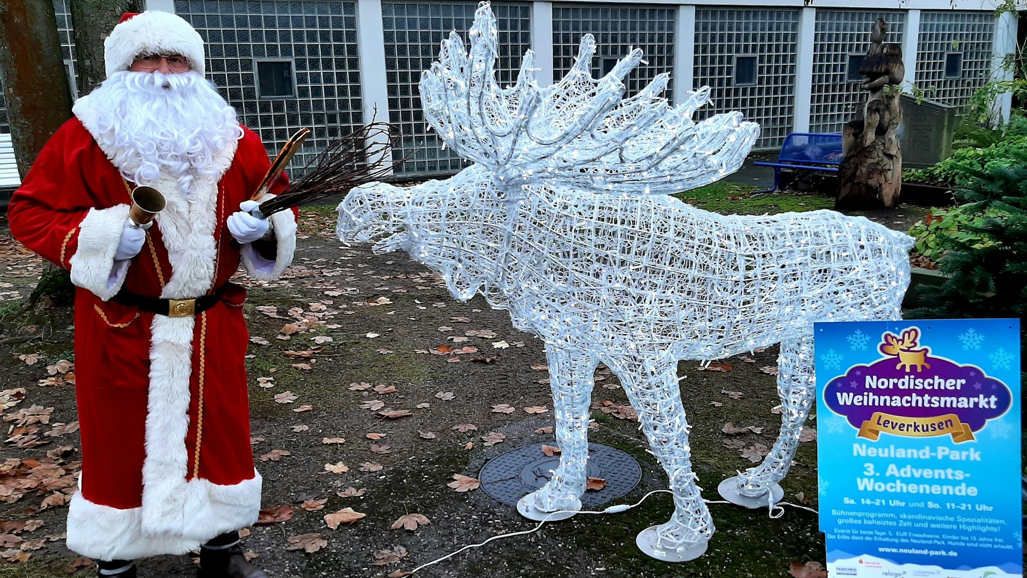Ein als Weihnachtsmann verkleideter Mann steht mit Rute vor einem Drahtelch.