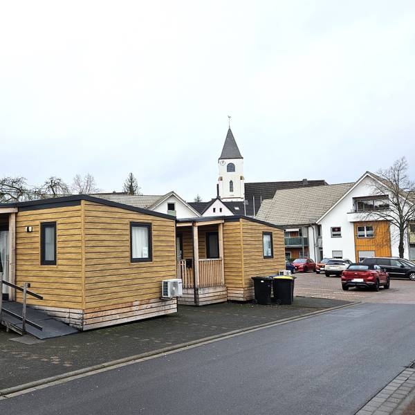 Blick auf zwei Tiny Houses, im Hintergrund ist die Kaller Kirche zu sehen.