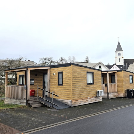 Blick auf zwei Tiny Houses, im Hintergrund ist die Kaller Kirche zu sehen.