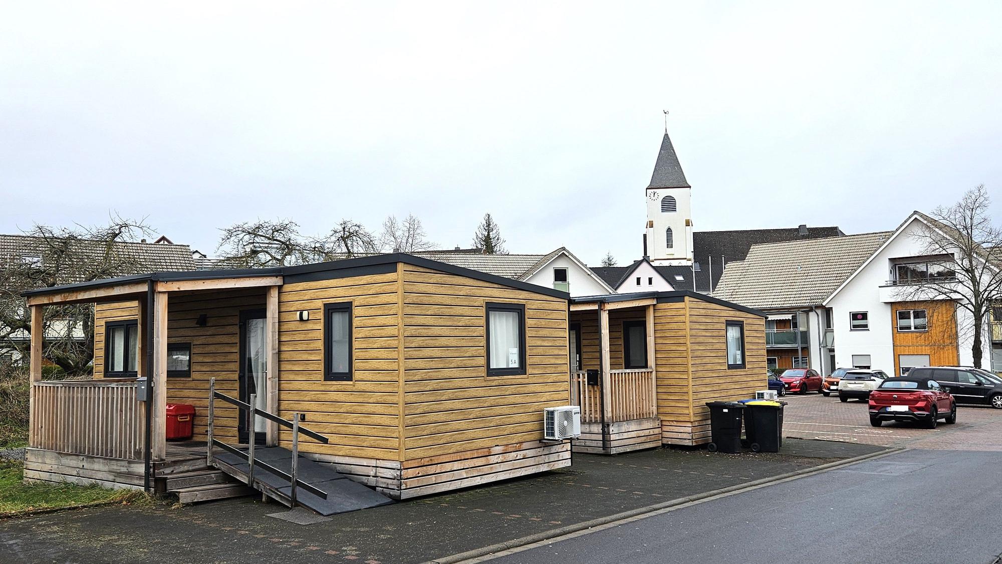 Blick auf zwei Tiny Houses, im Hintergrund ist die Kaller Kirche zu sehen.