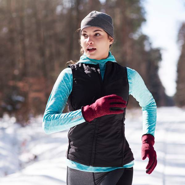 Eine junge Frau joggt durch einen verschneiten Wald