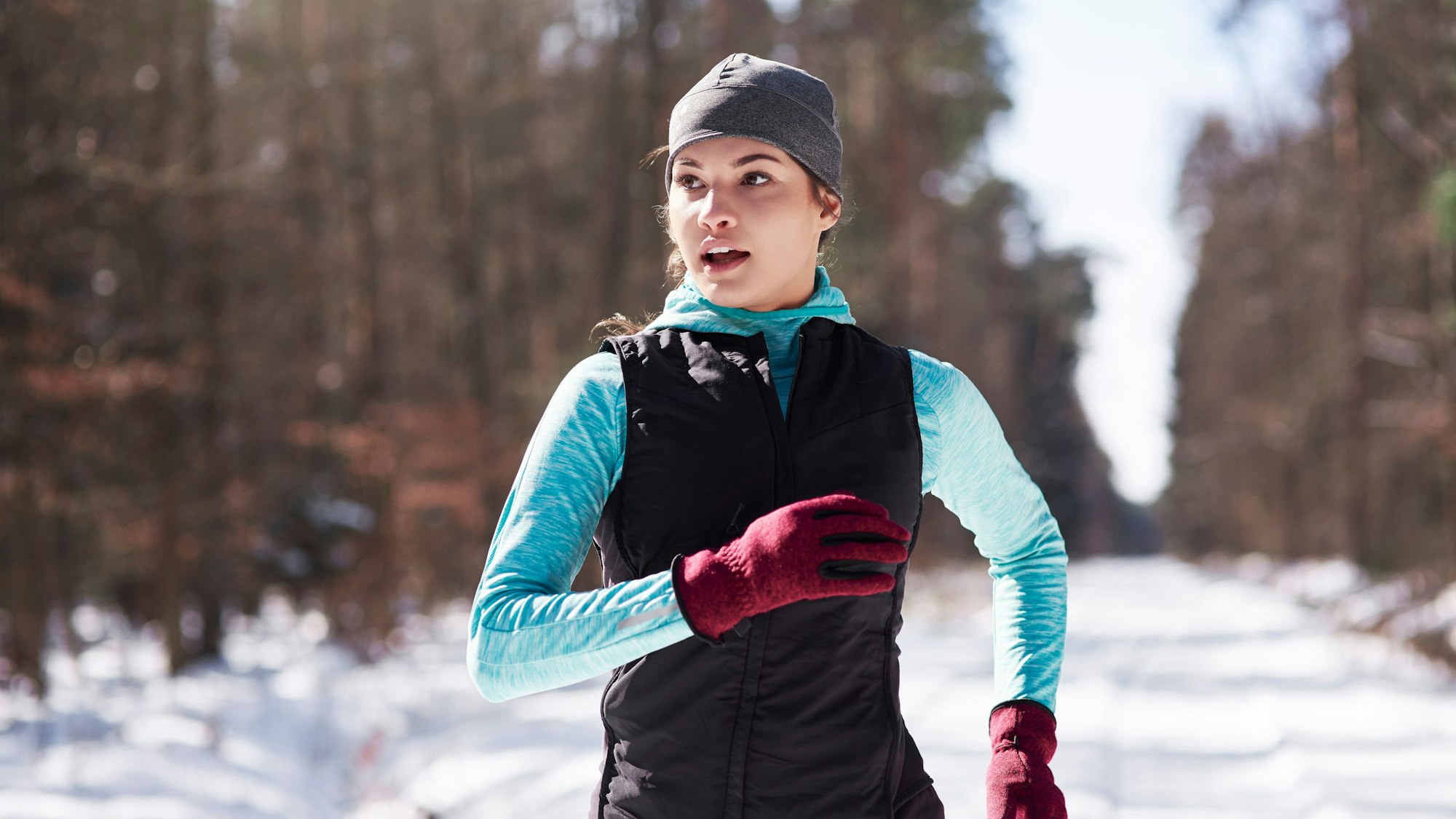 Eine junge Frau joggt durch einen verschneiten Wald