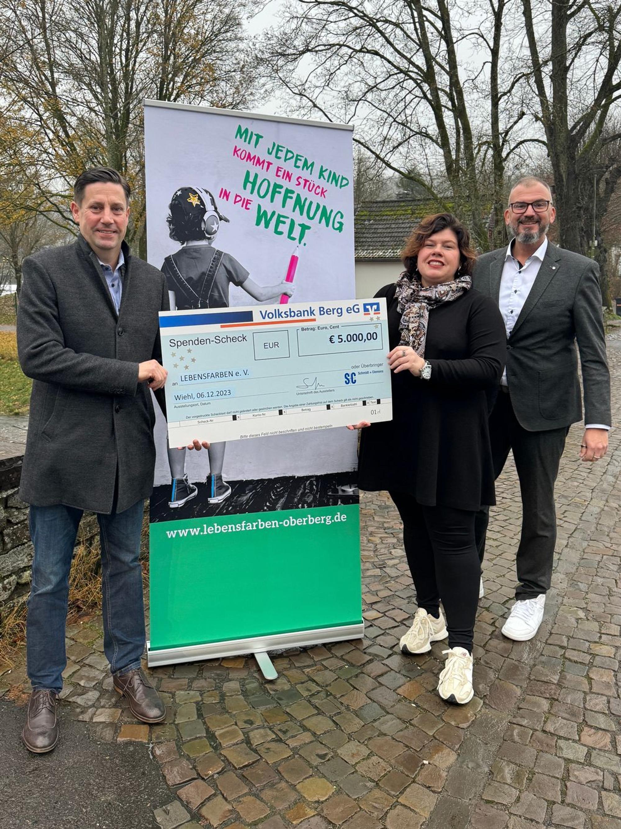 Jan Schmidt-Krayer übergibt einen großen Spendenscheck an Sandra Karsten vom Verein Lebensfarben.
