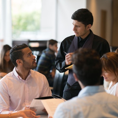 Ein Mann gibt im Restaurant bei einem Kellner eine Bestellung auf.