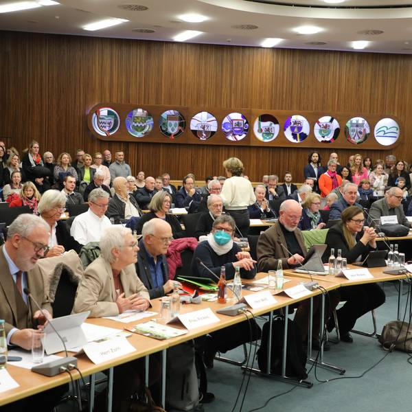 Bei der Kreistagsitzung 7. Dezember 2023 sitzen die gewählten Mandatsträger an ihren Tischen im Großen Kreissaal. Im Hintergrund stehen zahlreiche Besucher.