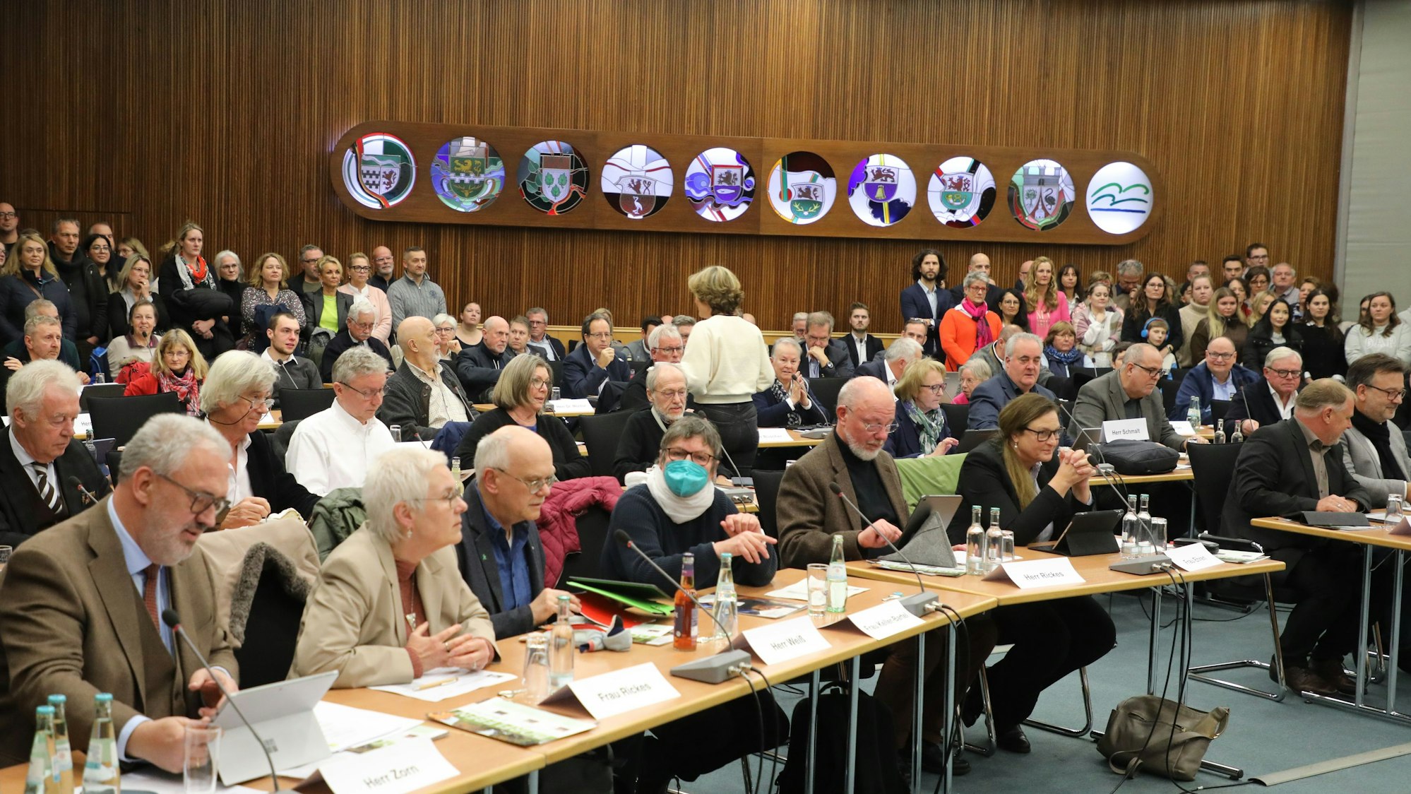 Bei der Kreistagsitzung 7. Dezember 2023 sitzen die gewählten Mandatsträger an ihren Tischen im Großen Kreissaal. Im Hintergrund stehen zahlreiche Besucher.