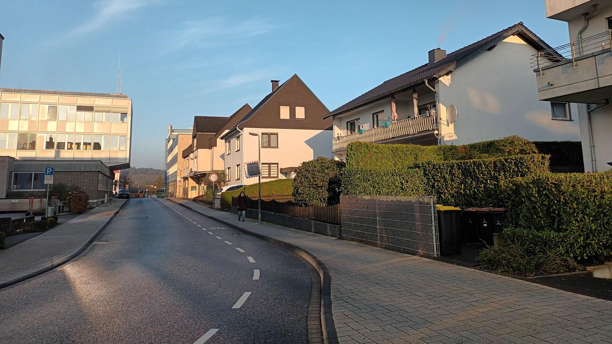Eine Straße mit Wohnhäusern, dem Lohmarer Rathaus und einer Bank.