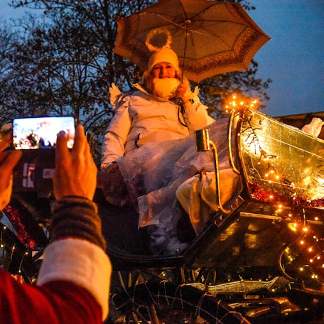 Eine Frau sitzt als Engel verkleidet auf einer Kutsche beim Lichterzug.