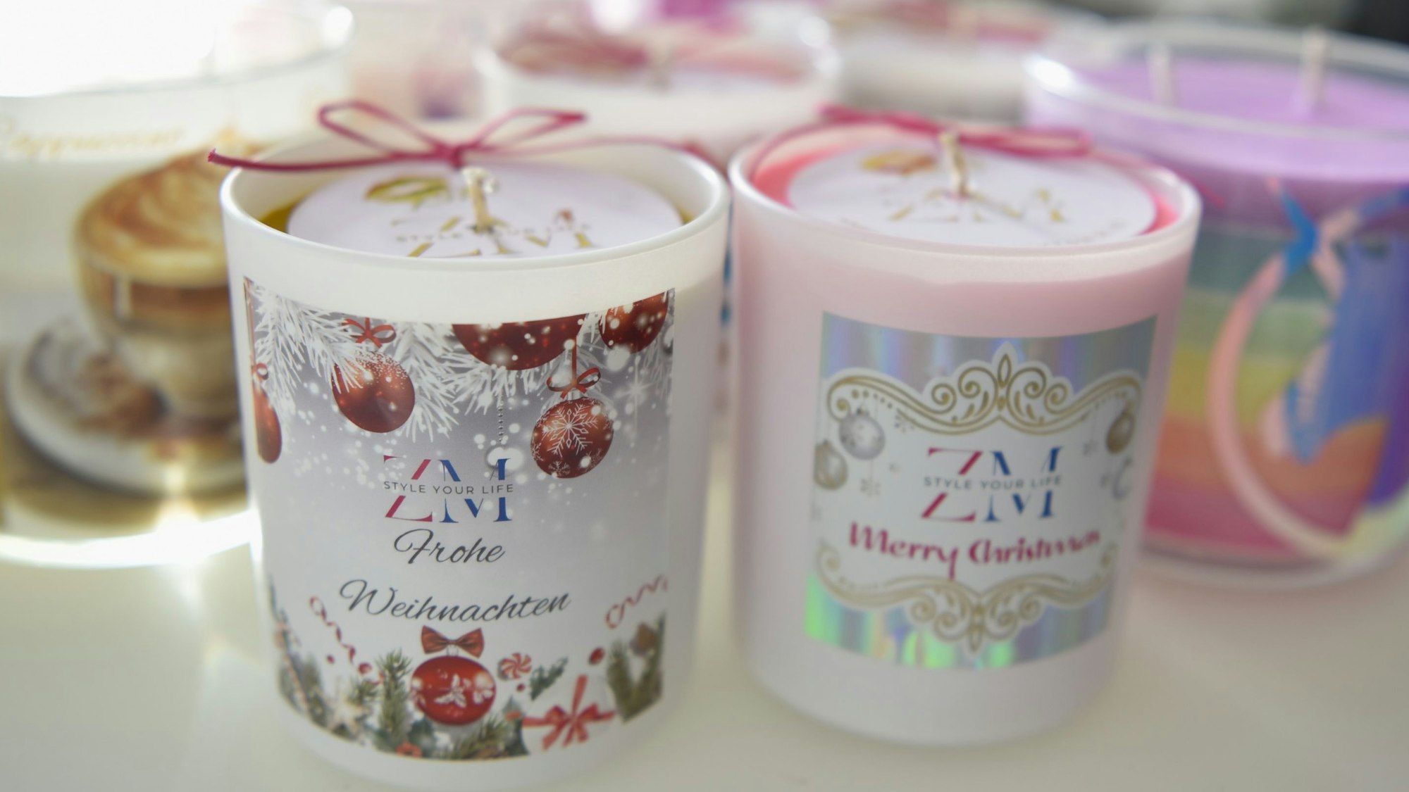 Verschiedene Duftkerzen stehen auf einem weißen Glastisch.