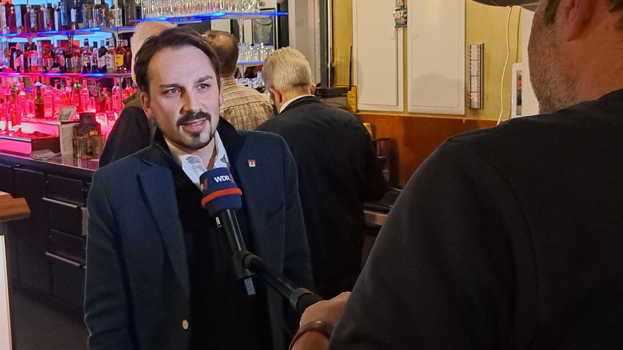 Matthias Großgarten steht an einem Mikrofon.