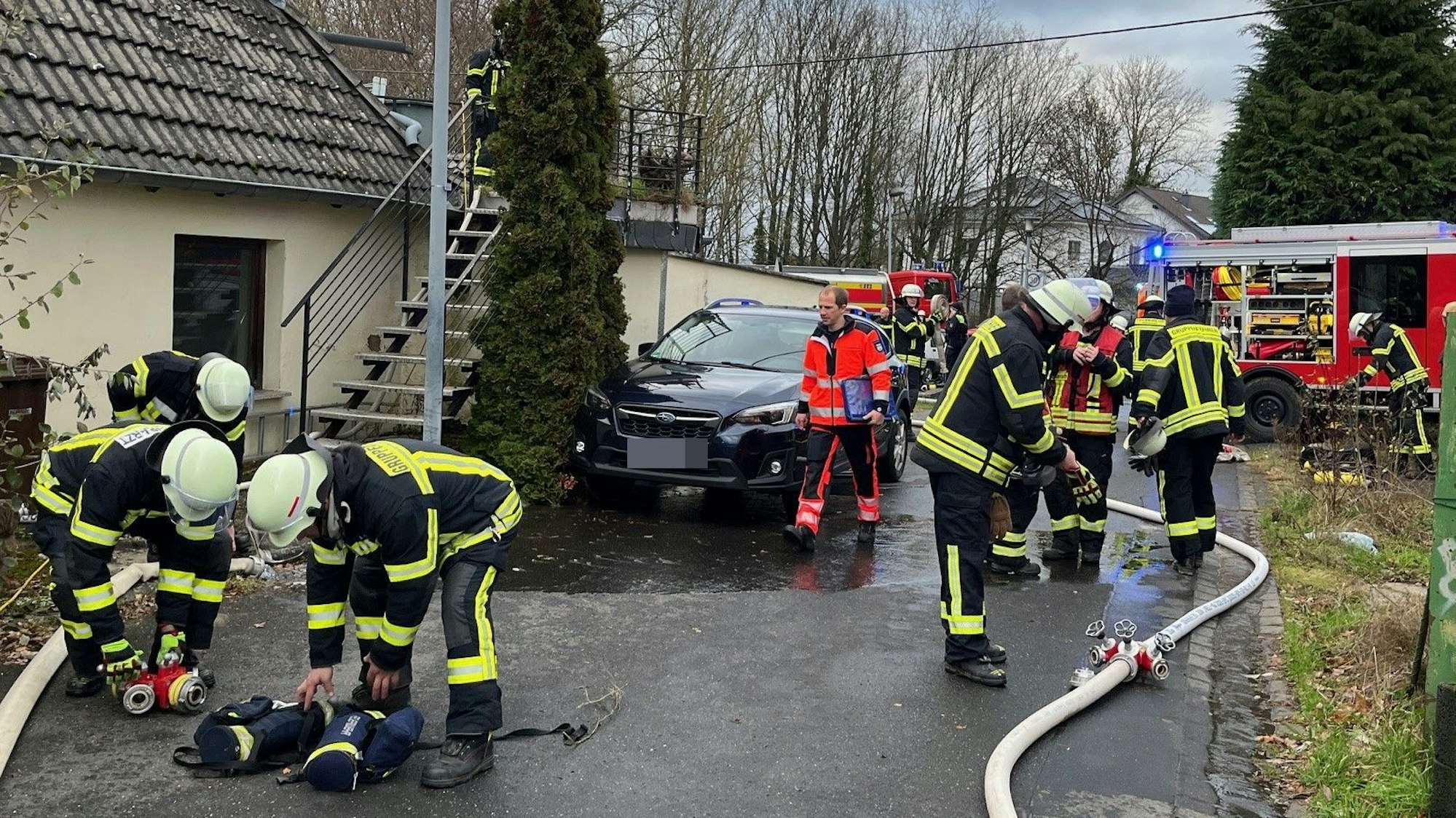 Mehrere Feuerwehrleute und Rettungskräfte in einer schmalen Straße.