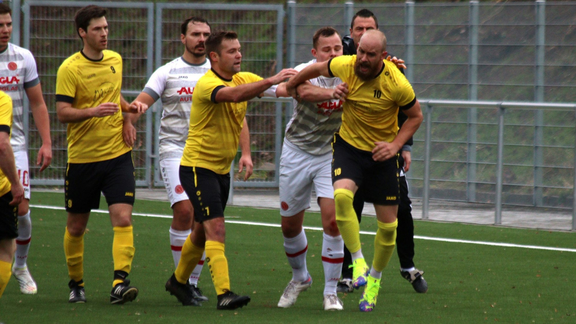 Rudelbildung: Bliesheims Martin Meisen stößt Dennis Fischer, der laut schreit und wutentbrannt dreinschaut. Fischer hatte Meisen zuvor zu Boden gestoßen. Andere Spieler greifen ein.