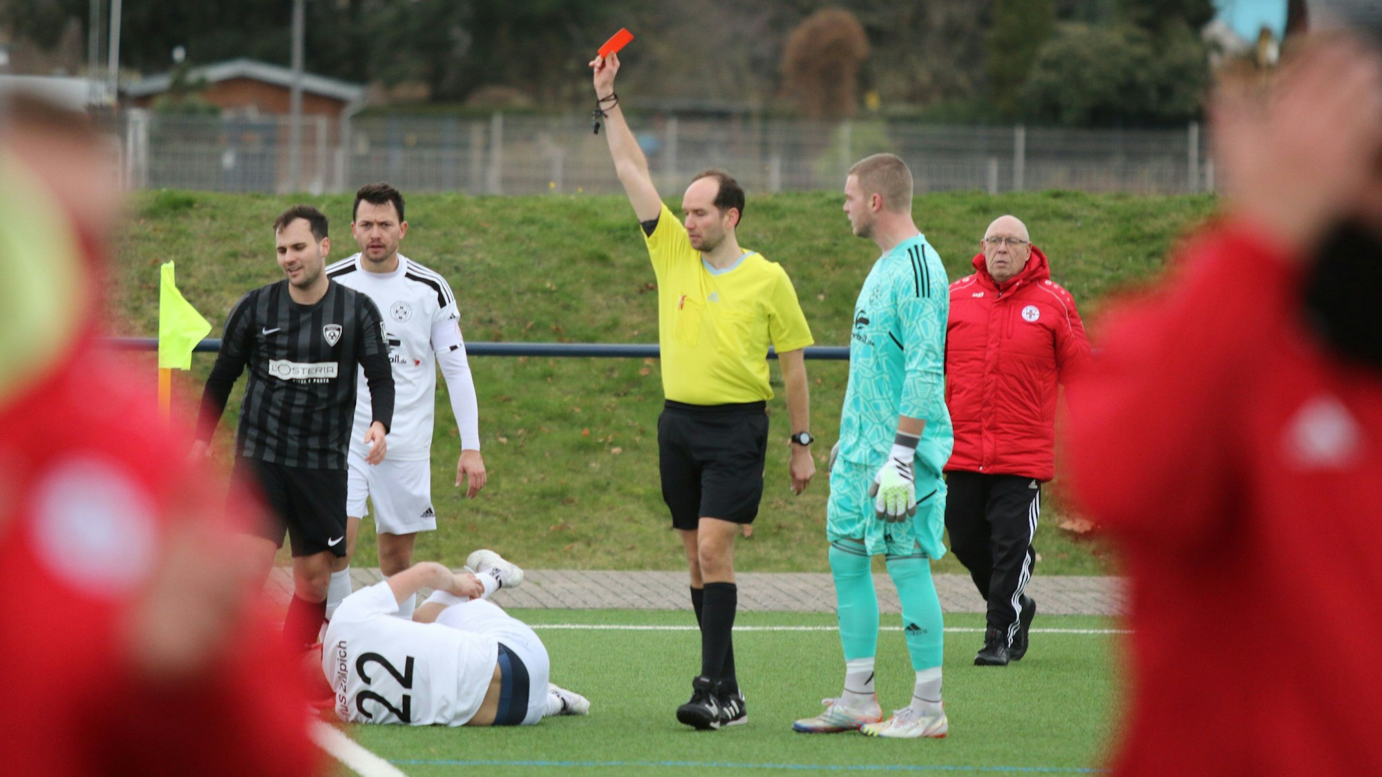 Der Schiedsrichter zeigt Lein Reimer die Rote Karte. Vor ihm auf dem Boden liegt Marco Weinhold, der sich das rechte Bein festhält.