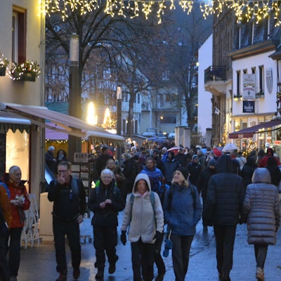 Menschen in dicken Jacken schlendern durch die weihnachtlich beleuchtete Innenstadt von Bad Münstereifel.
