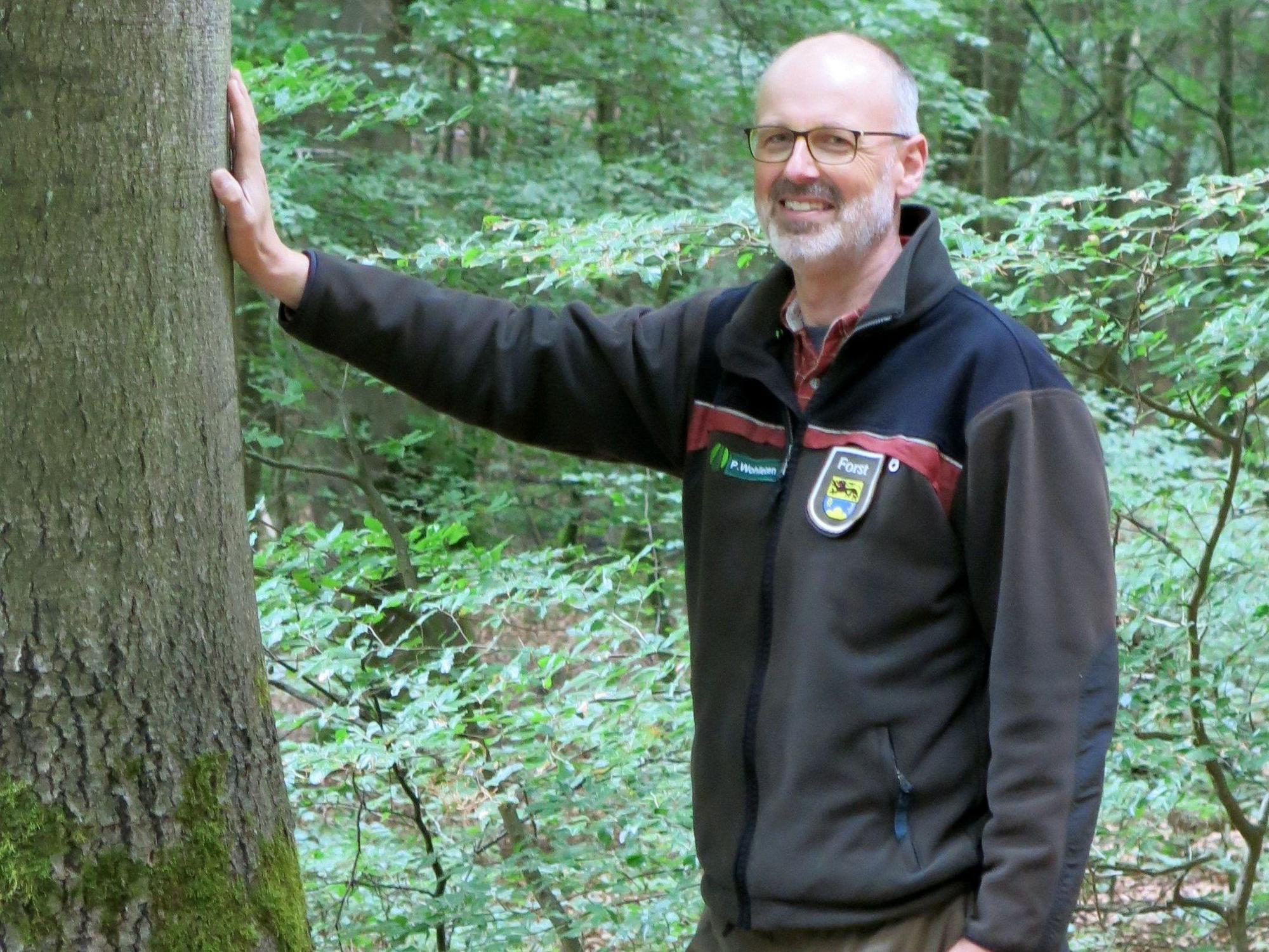 Der Förster Peter Wohlleben lehnt an einem Baum im Wald rund um die Eifelgemeinde Hümmel.