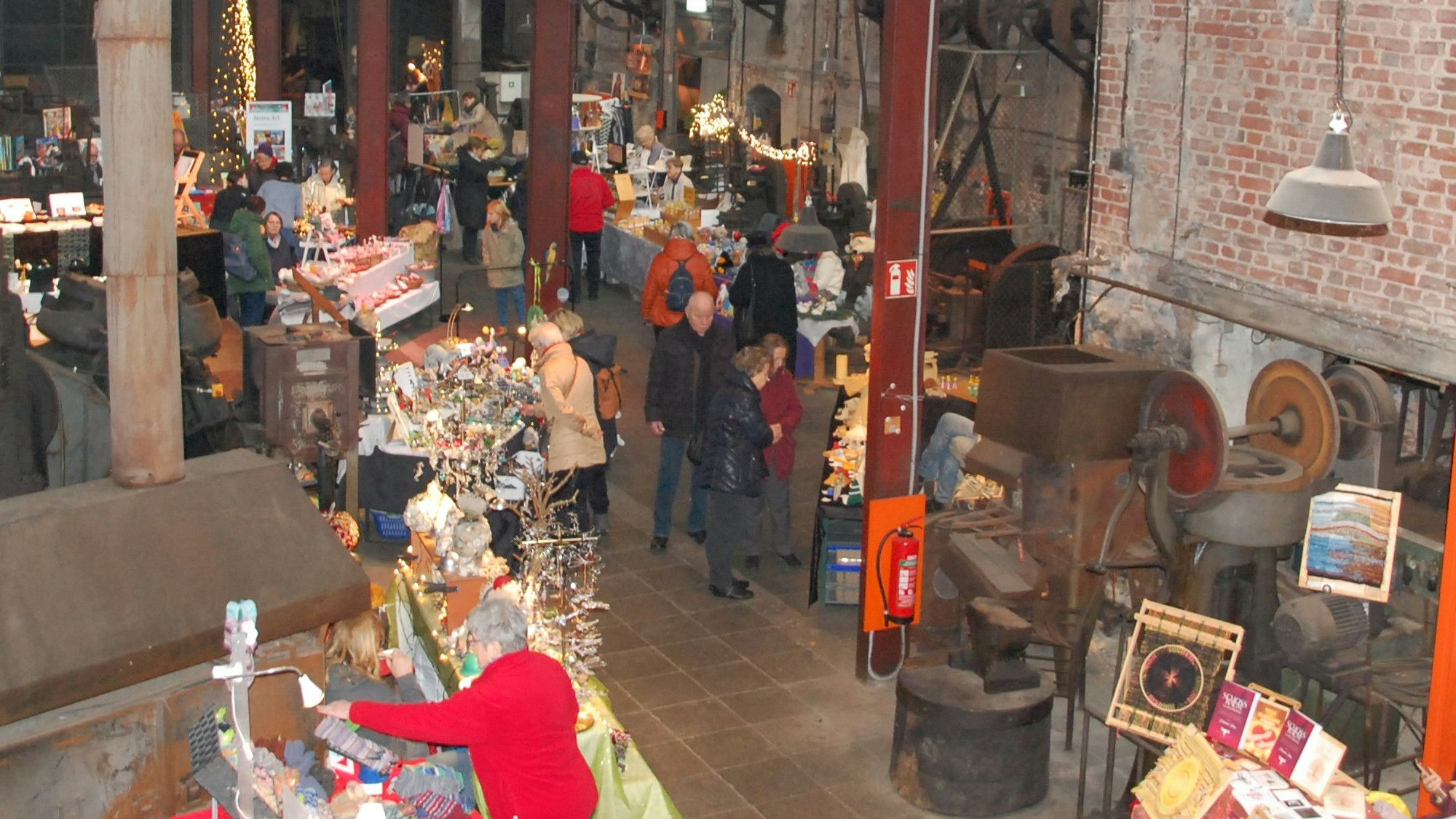 Menschen gehen zwischen Ständen im Freudenthaler Sensenhammer hin und her.