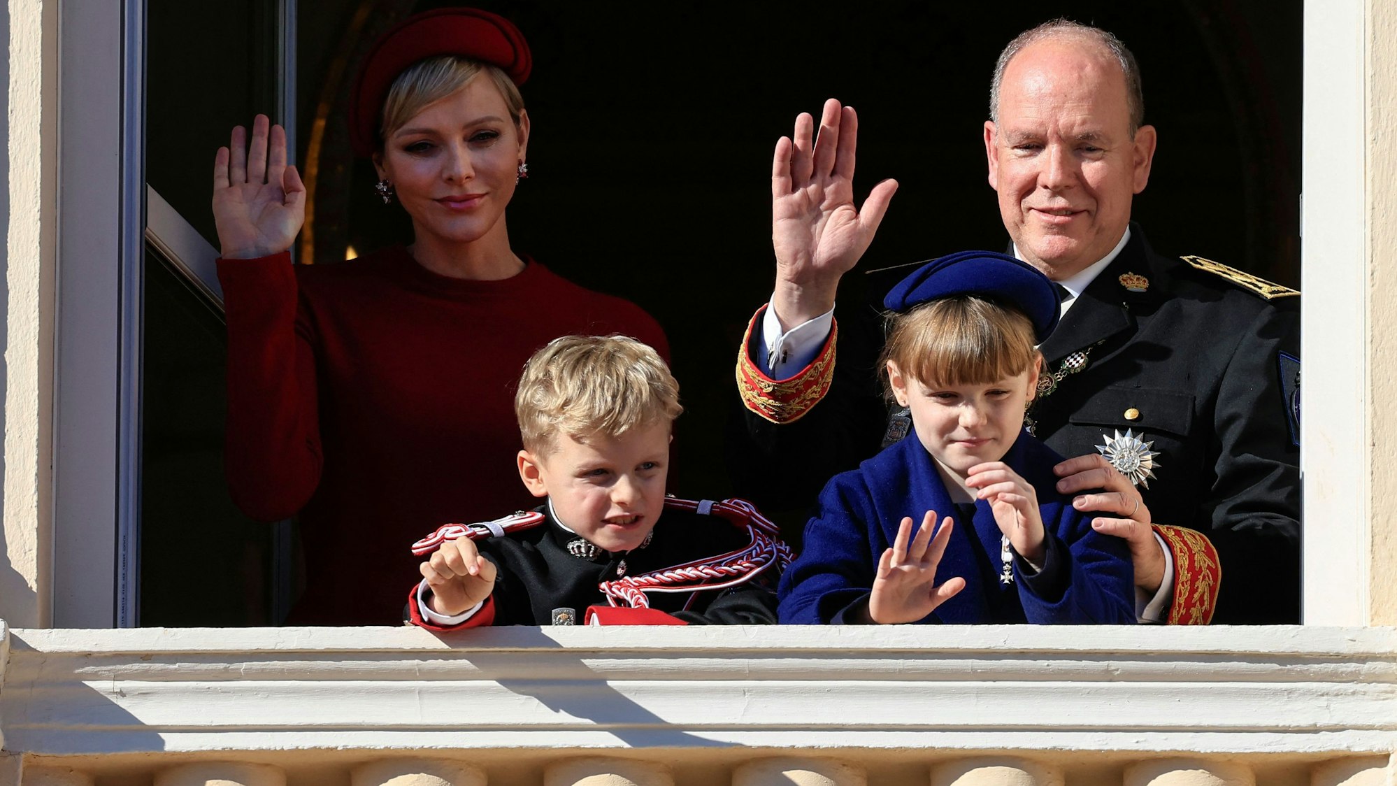 Fürstin Charlène von Monaco (hinten l), Fürst Albert II. von Monaco (hinten r), Fürst Jacques von Monaco (vorne l) und Fürstin Gabriella (vorne r) winken vom Balkon des Fürstenpalastes von Monaco während einer Zeremonie zum Nationalfeiertag in Monaco am 19. November 2023.