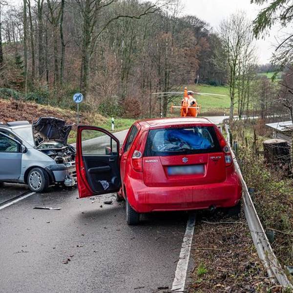 Das Foto zeigt zwei schwer beschädigte Pkw und einen Rettungshubschrauber