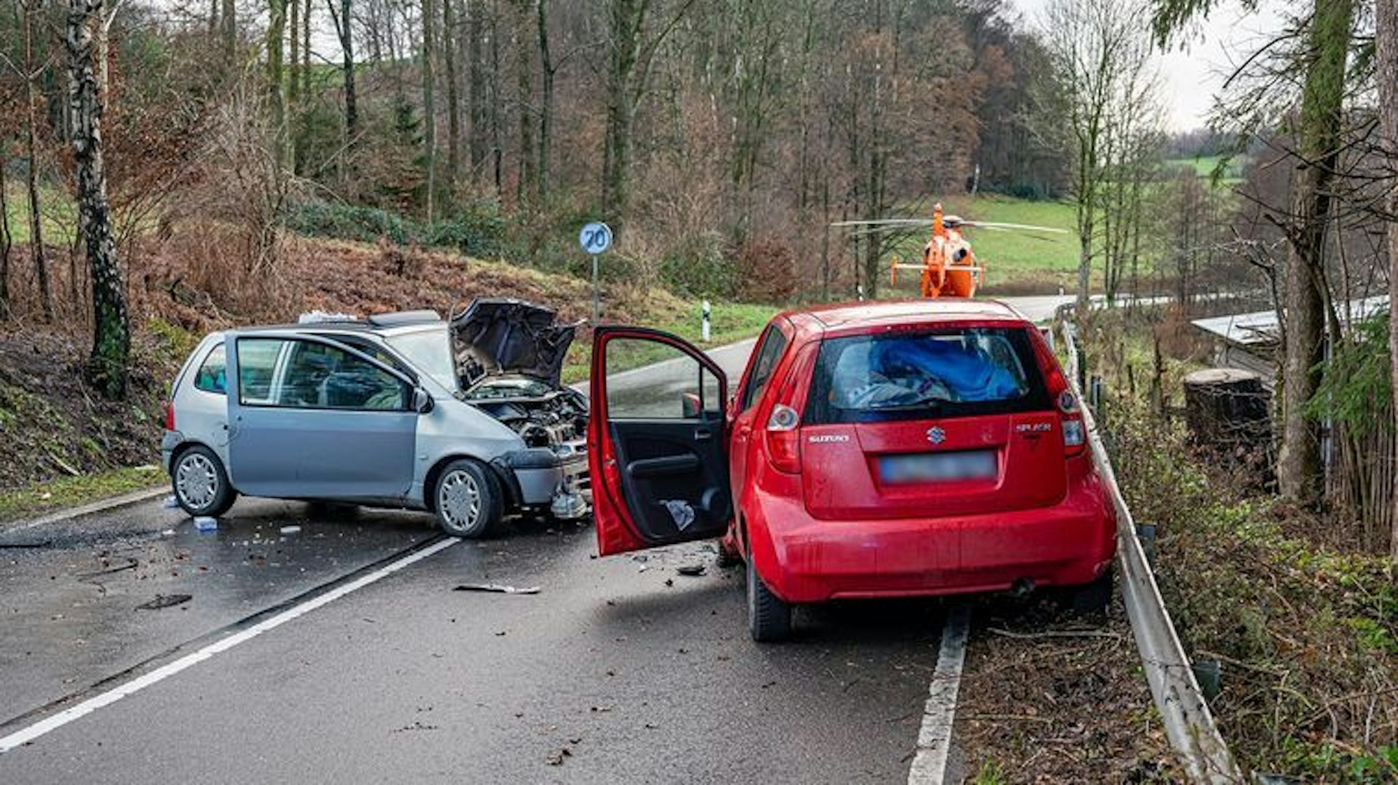 Das Foto zeigt zwei schwer beschädigte Pkw und einen Rettungshubschrauber
