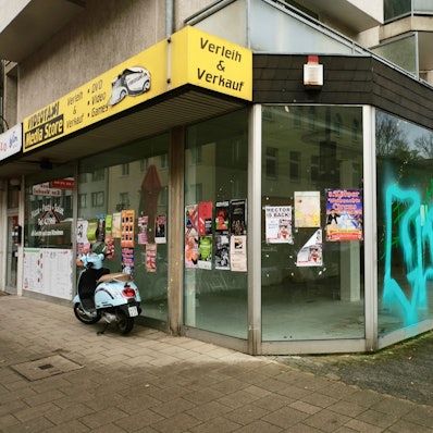 Glasfront eines Ladenlokals, mit Plakaten beklebt und Graffiti beschmiert.