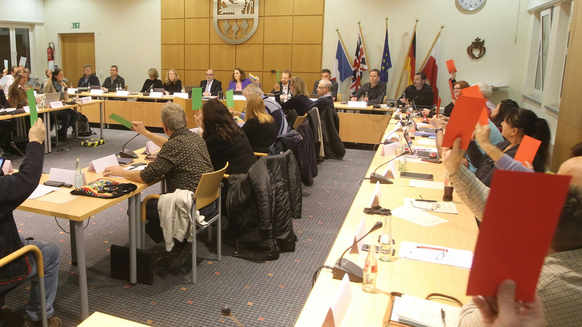 Männer und Frauen in einem Sitzungssaal bei einer Abstimmung.