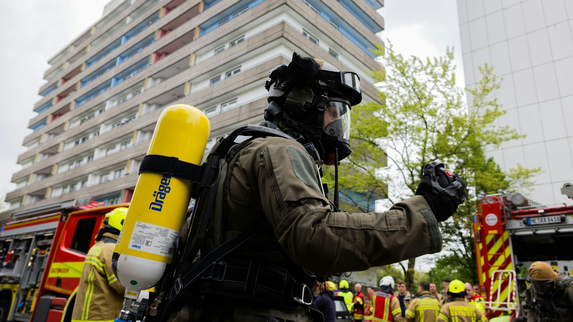 Polizeibeamte mit Gasmasken und Feuerwehrleute stehen vor einem Hochhaus. Bei einer Explosion in einem Hochhaus in Ratingen am 11. Mai 2023 wurden mehrere Menschen verletzt - darunter auch Polizisten und Einsatzkräfte der Feuerwehr.
