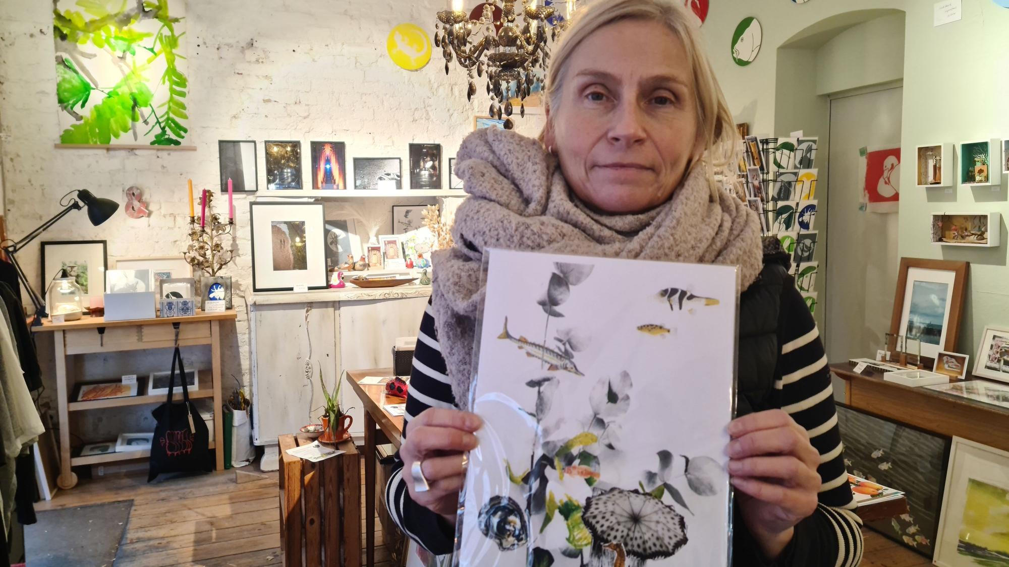 Eine Frau mit Schal hält ein buntes Bild hoch