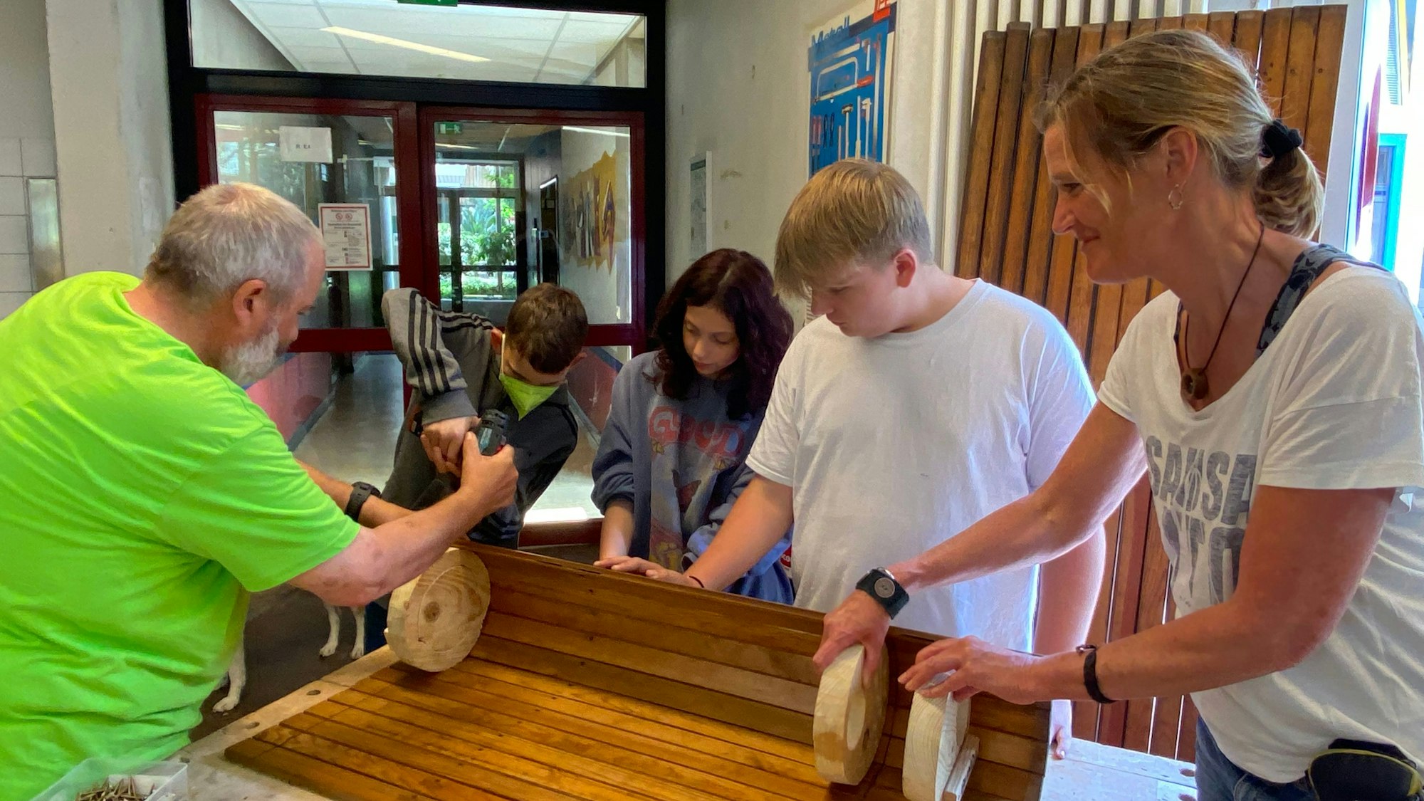 Zu sehen sind Lehrer und Schüler beim Bau eines Nistkastens.