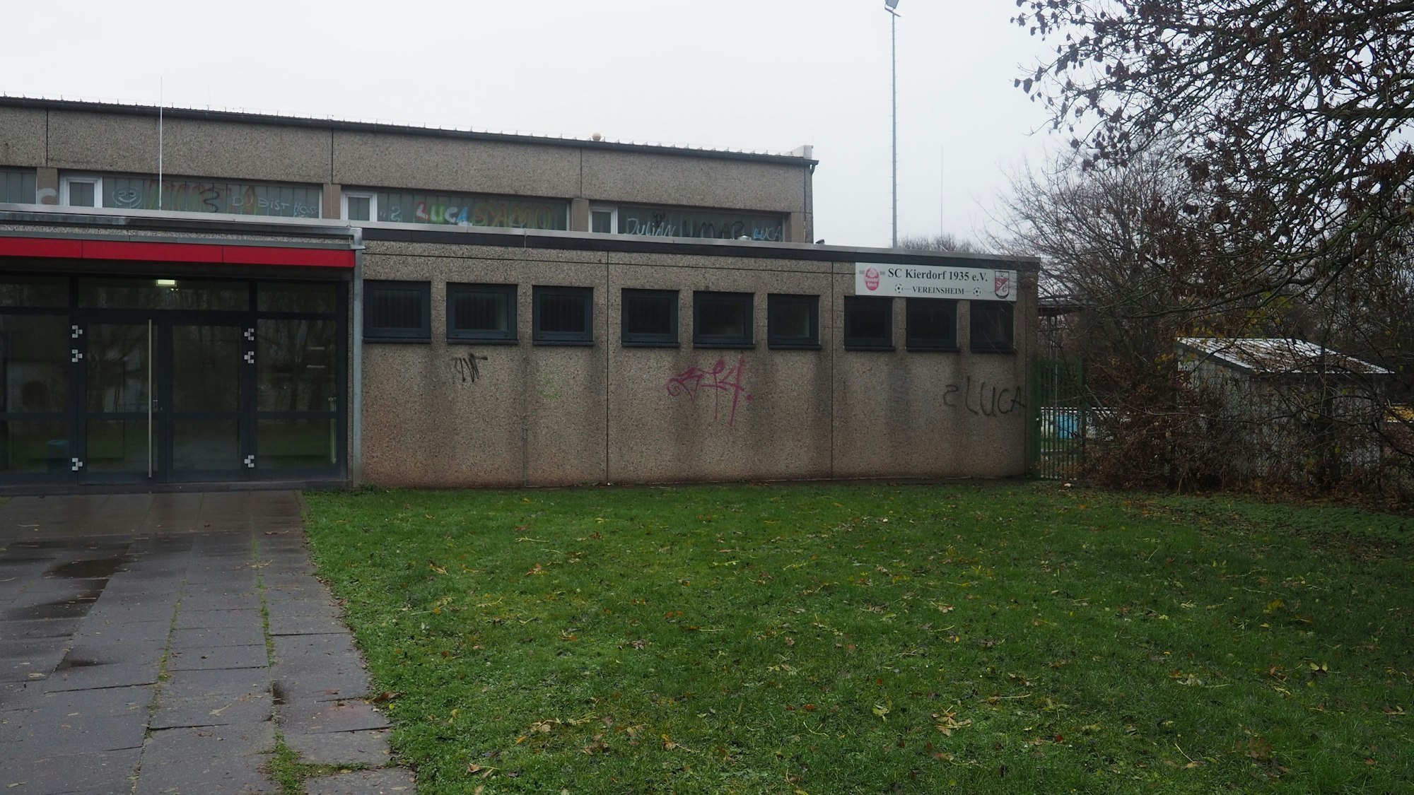 Auf dem Foto sind die Umkleidekabinen von außen zu sehen. An der Wand ist Graffiti aufgesprüht.