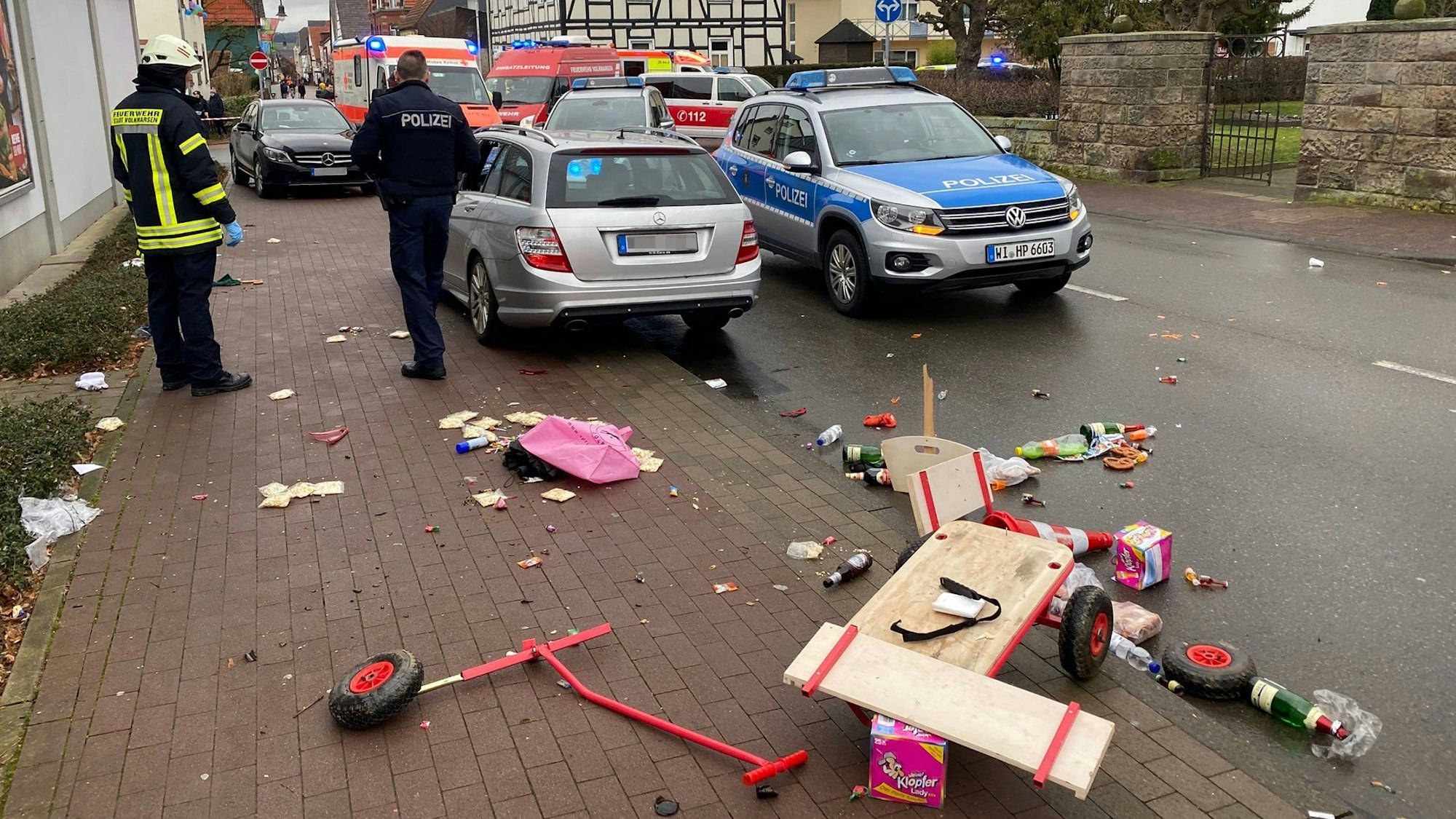 Ein zerbrochener Handkarren liegt auf der Straße, dahinter Wagen der Polizei, der Feuerwehr und ein Krankenwagen.